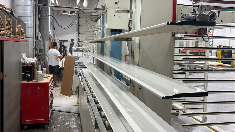 Freshly primed poplar baseboard on the rack at White River, with the priming line behind it