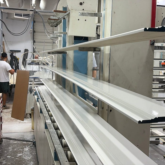 Freshly primed poplar baseboard on the rack at White River, with the priming line behind it